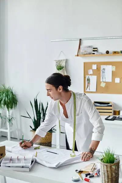 A young tailor, dressed in a white shirt, works on a clothing project in his DIY atelier. — Stock Photo