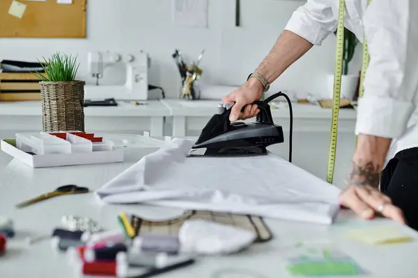Un jeune homme repasse méticuleusement un morceau de tissu dans son atelier de restauration de vêtements de bricolage. — Photo de stock