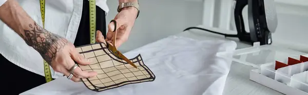 Un joven corta cuidadosamente un trozo de tela, reutilizando la ropa vieja para un enfoque sostenible y elegante de la moda. - foto de stock