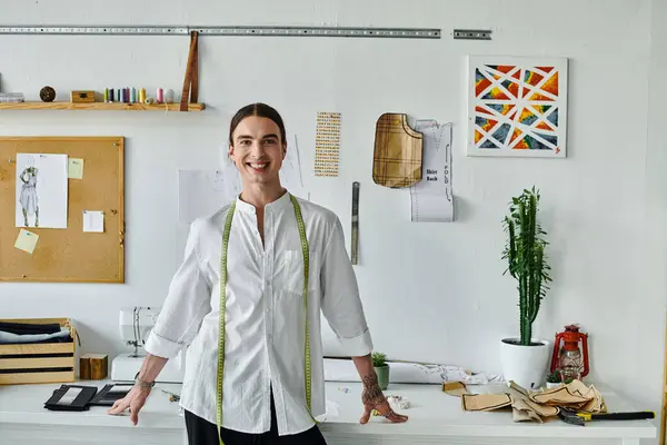 A young man smiles confidently in his DIY clothing restoration atelier, showcasing his passion for sustainable fashion and giving new life to old clothes. — Stock Photo