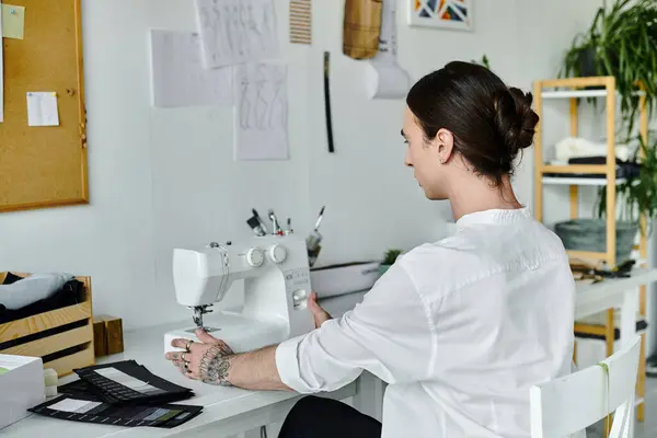 A young man works on a sewing machine in his clothing restoration atelier, focused on giving new life to old items. — Stock Photo