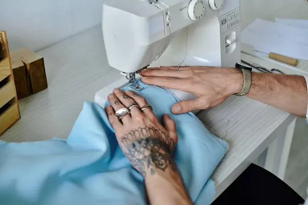 Un joven cose meticulosamente una prenda en su máquina de coser, demostrando su compromiso con la sostenibilidad y restaurando la ropa vieja. - foto de stock