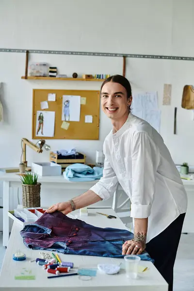 A young man smiles proudly as he showcases his upcycled clothing in his DIY atelier. — Stock Photo