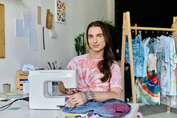 A young man operates a sewing machine in his atelier, focused on reviving discarded clothing with sustainable techniques. — Stock Photo
