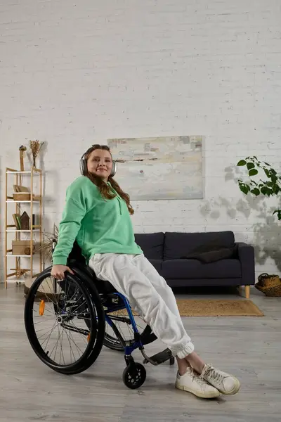 Uma jovem morena senta-se em uma cadeira de rodas em sua sala de estar. — Fotografia de Stock