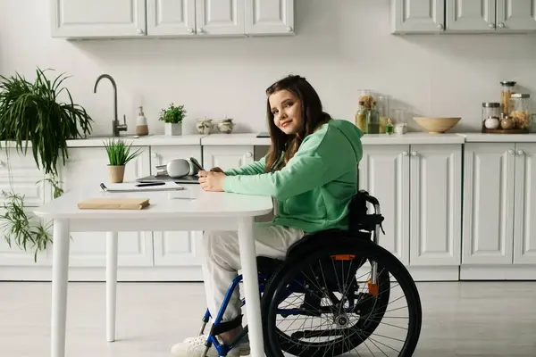 A young brunette woman in a wheelchair sits at a table in her homes living room, smiling. — Stock Photo