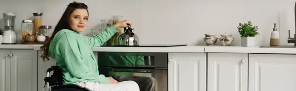 Une jeune femme en fauteuil roulant s'assoit dans sa cuisine, préparant le café le matin. — Photo de stock
