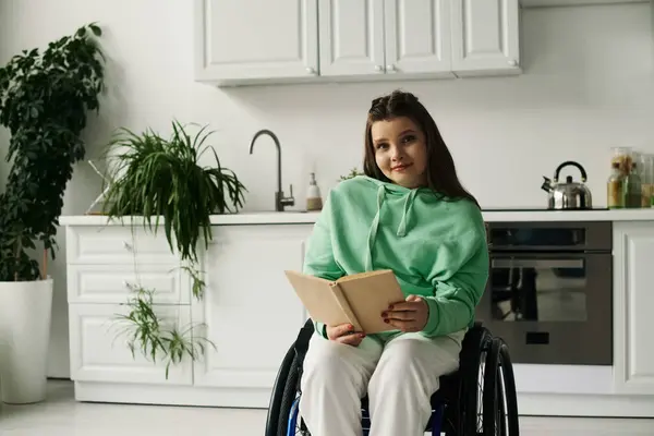 Молода брюнетка в інвалідному візку сидить у своїй вітальні, насолоджуючись книгою. — стокове фото