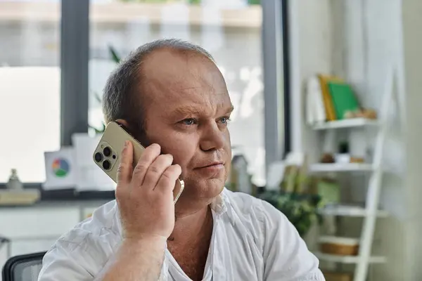 A man with inclusivity in a white shirt talks on his phone in a professional office setting. — Stock Photo