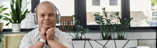 A man with inclusivity wearing headphones sits at a desk in an office. — Stock Photo