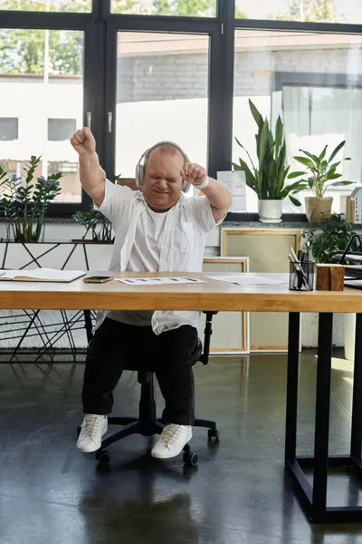 A man with inclusivity in an office setting dances while wearing headphones, enjoying a moment of fun. — Stock Photo