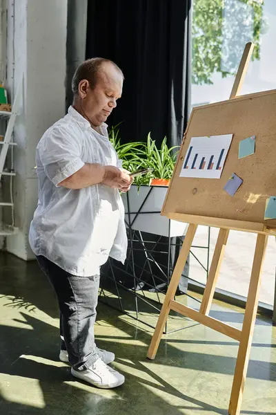 A man with inclusivity reviews a chart on an board in a modern office setting. — Stock Photo