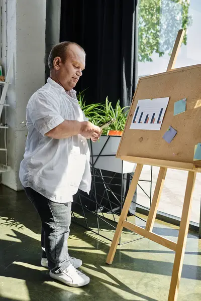 A man with inclusivity stands in front of a board in an office, presenting data. — Stock Photo