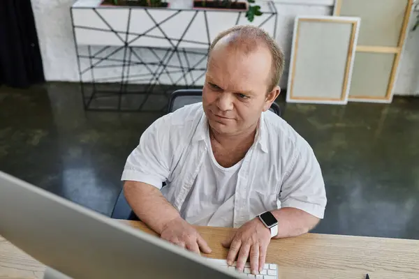 A man with inclusivity in a white shirt works on a computer in an office setting. — Stock Photo