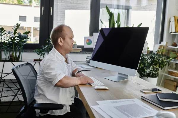 A man with inclusivity sits at his desk, working on a computer in a modern office. — Stock Photo