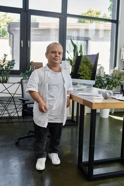 A man with inclusivity confidently stands in an office setting, showcasing inclusivity and diversity in the workplace. — Stock Photo