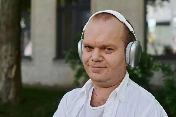 A man with inclusivity wearing headphones, listening to music while enjoying a walk outdoors. — Stock Photo