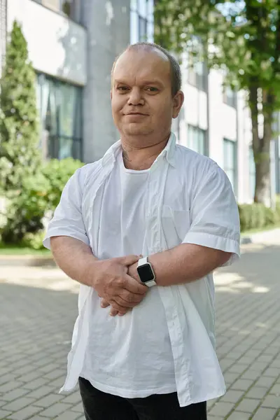 Человек с включённостью в белой рубашке стоит на городской улице. — стоковое фото