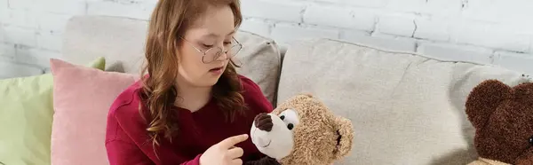 Una bambina con la sindrome di Down passa del tempo a casa con il suo orsacchiotto. — Foto stock