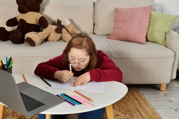 Ein kleines Mädchen mit Down-Syndrom greift zu Hause zum Notizbuch. — Stockfoto