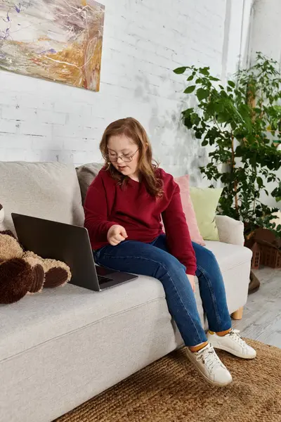A little girl with Down syndrome relaxes on the couch at home. — Stock Photo
