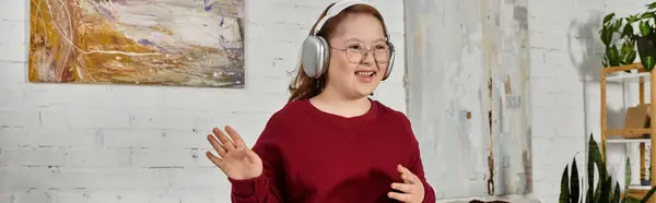 A little girl with Down syndrome enjoys music and dances in her living room. — Stock Photo