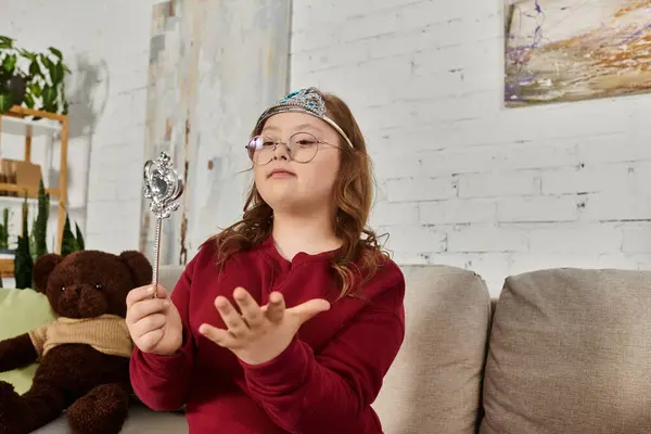 A little girl with Down syndrome plays with a magic wand while wearing a crown. — Stock Photo