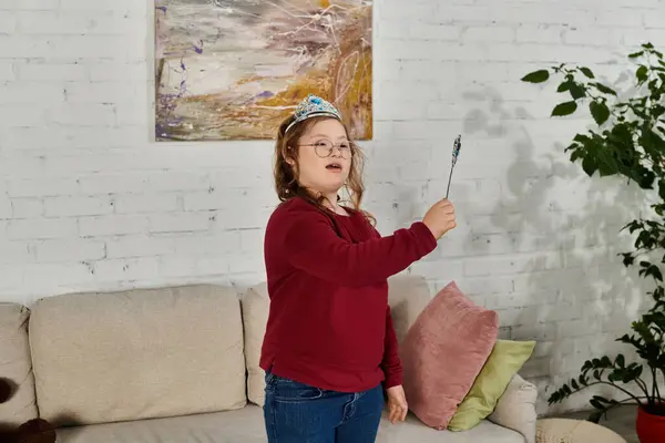 A little girl with Down syndrome plays with a wand while wearing a crown. — Stock Photo