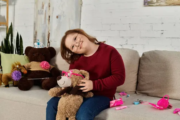 A little girl with Down syndrome plays with her toy animals on a couch in her home. — Stock Photo