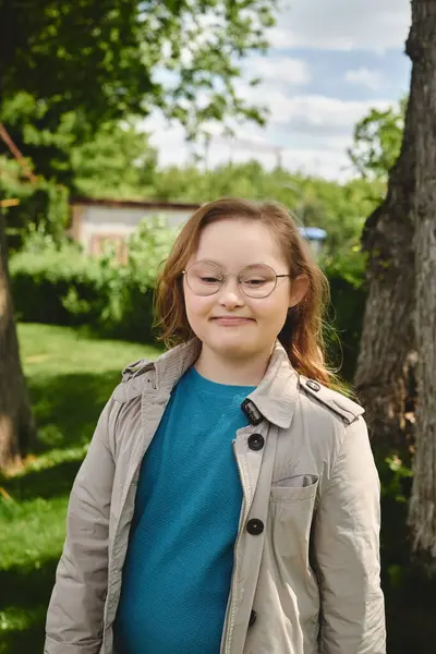 A little girl with Down syndrome stands outside her home, smiling brightly. — Stock Photo