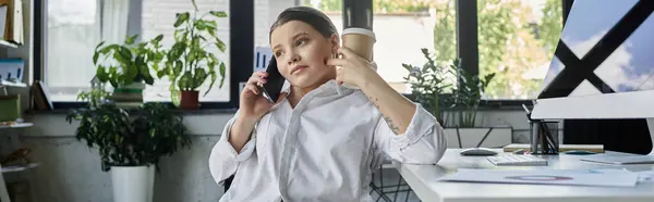 Молода бізнес-леді з інвалідністю сидить в інвалідному візку в сучасному офісі, працює і розмовляє по телефону. — стокове фото