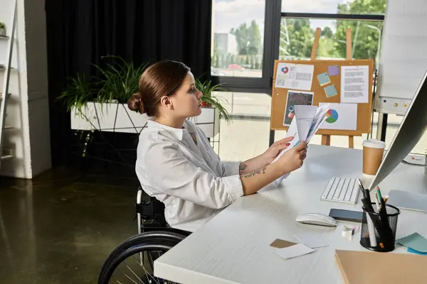 A disabled businesswoman in a wheelchair reviews documents in a modern office. — Stock Photo