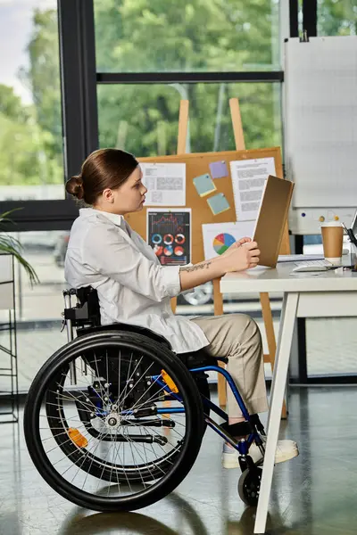 Молодая деловая женщина в инвалидной коляске работает за своим столом в современном офисе. — стоковое фото