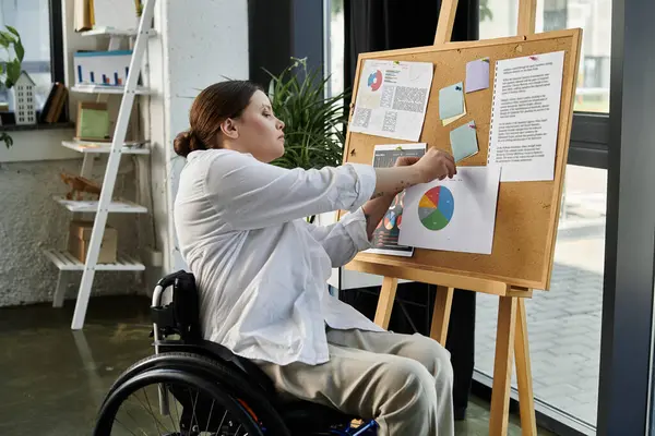 A young businesswoman in a wheelchair works on a project in a modern office setting. — Stock Photo