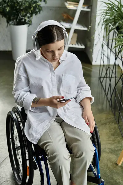 Una joven empresaria en silla de ruedas trabaja en una oficina moderna. - foto de stock