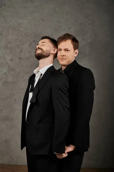 Two men in elegant suits stand close together against a gray backdrop. — Stock Photo