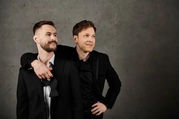 Two men in elegant suits pose for a photograph against a grey backdrop. — Stock Photo