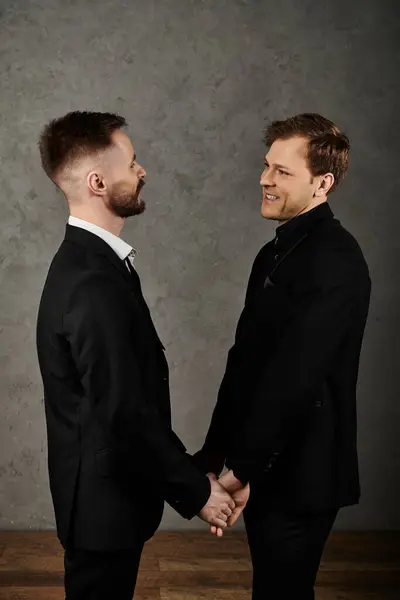 Two men in dapper suits stand close, holding hands, with a loving gaze. — Stock Photo