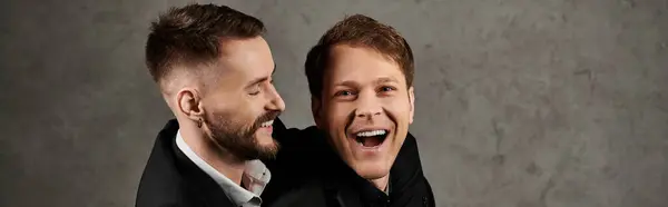 Two men in suits laugh together against a textured concrete wall. — Stock Photo