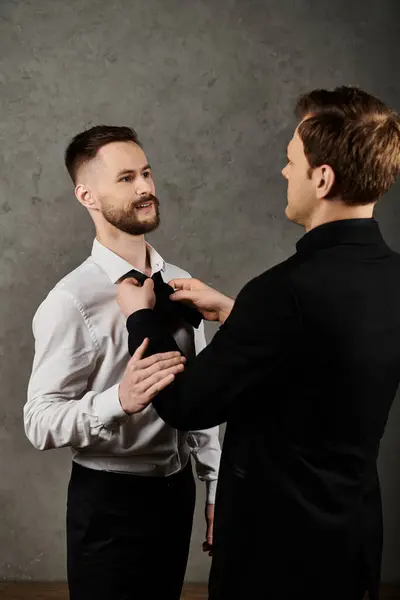Two men in suits, one adjusting the others bow tie, showcasing love and intimacy before an event. — Stock Photo