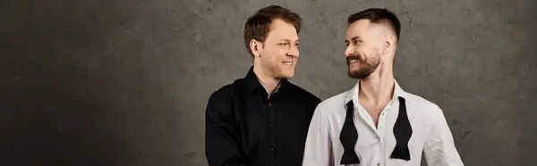 Due uomini in abiti eleganti, uno nero, uno bianco, sorridono affettuosamente. — Foto stock