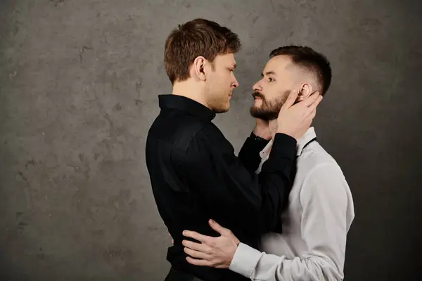 Ein schwules Paar in eleganten Anzügen, das einen intimen Blick und eine zarte Berührung teilt. — Stockfoto