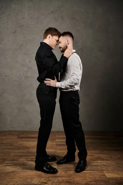 Loving gay couple in dapper suits, touching foreheads, show affection in embrace. — Stock Photo
