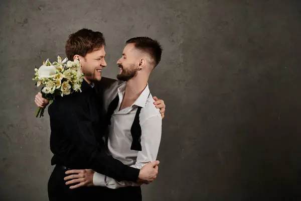 Two men in elegant suits embrace, one holding a bouquet of white flowers. — Stock Photo