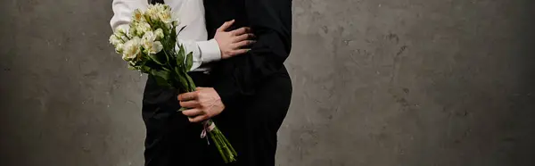 Two men in sharp suits embrace, one holding flowers. — Stock Photo