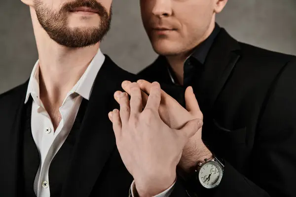 Two men in elegant suits hold hands, their fingers intertwined. — Stock Photo
