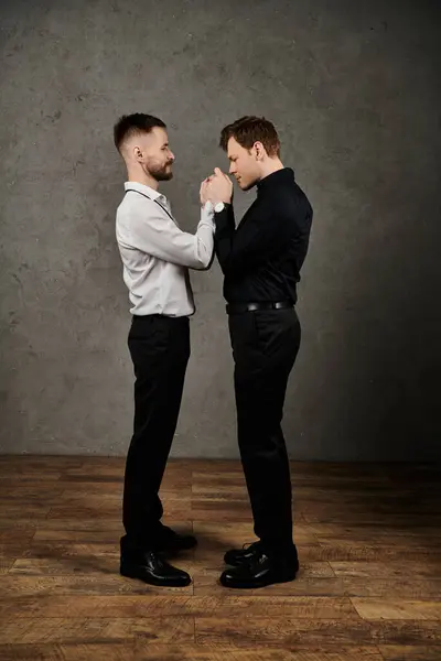 Two men in suits stand close, holding hands. — Stock Photo