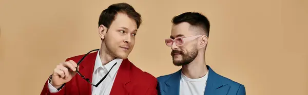 Two men in suits, one in red and one in blue, gaze at each other with affection. — Stock Photo