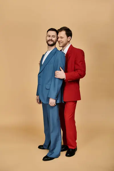 Two men in suits, one in blue and one in red, smile at each other. — Stock Photo