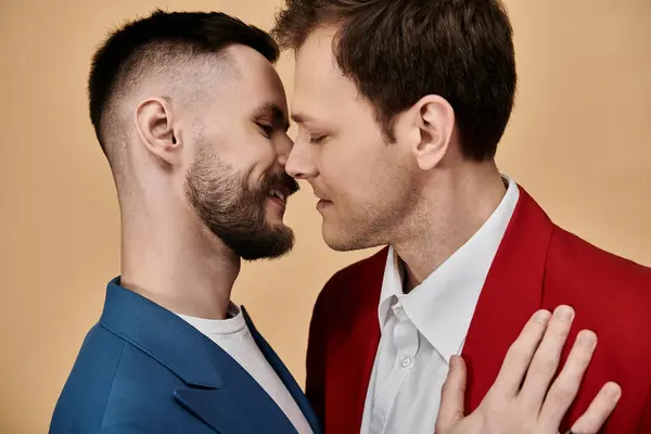 Dos hombres vestidos de traje se paran uno cerca del otro, compartiendo un momento de ternura. - foto de stock